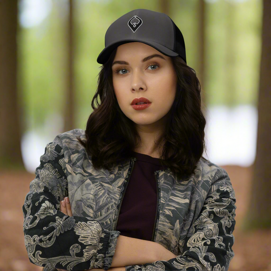 Woman wearing a black cap and patterned jacket against a plain background